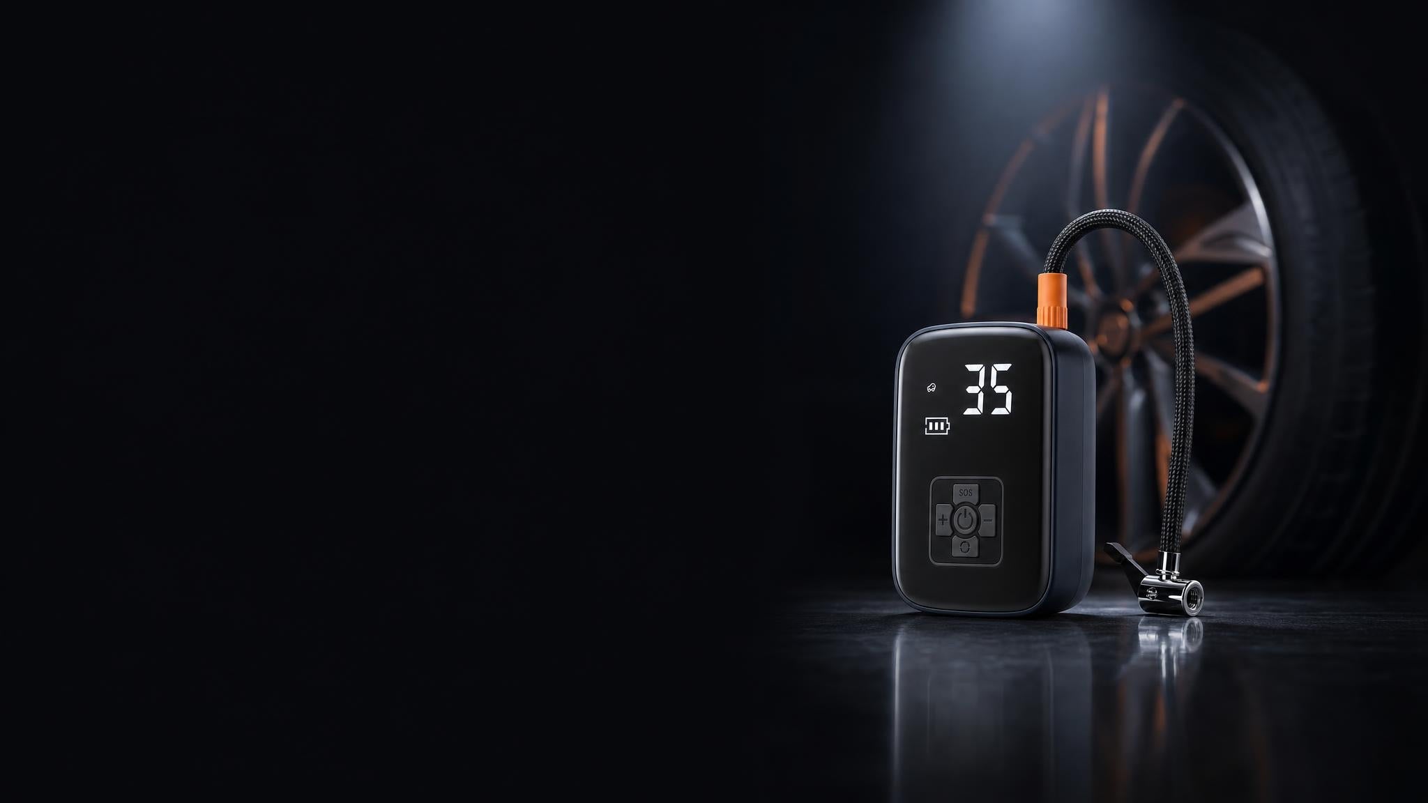 Cordless tire inflator glowing on a dark garage floor next to a car wheel
